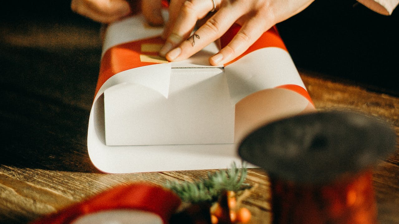 Person wrapping a gift with care and decorative ribbon