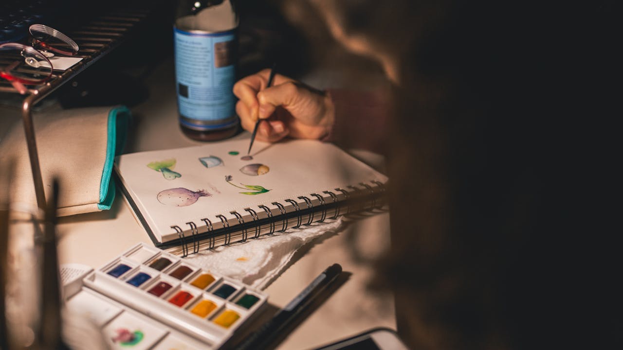 Hands painting with watercolors on white paper