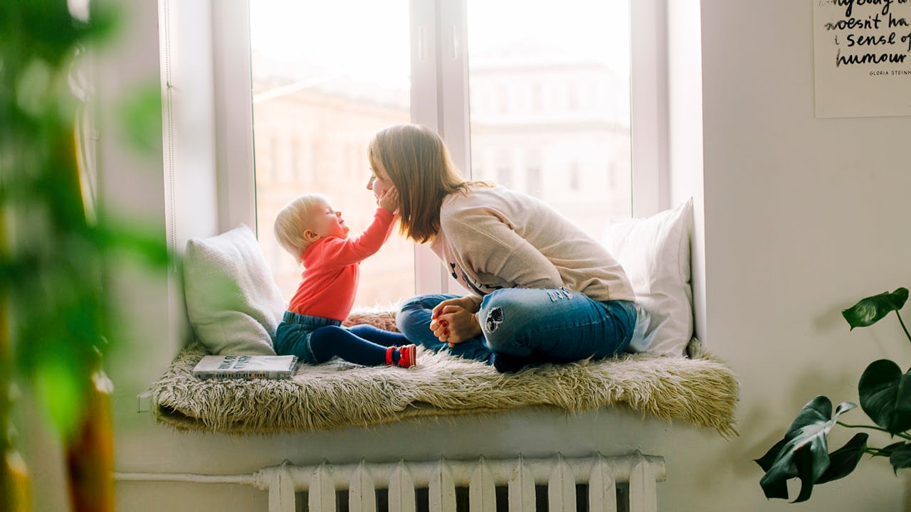 Father and baby daughter playing happily with colorful wooden stacking toys on a soft living room floor
