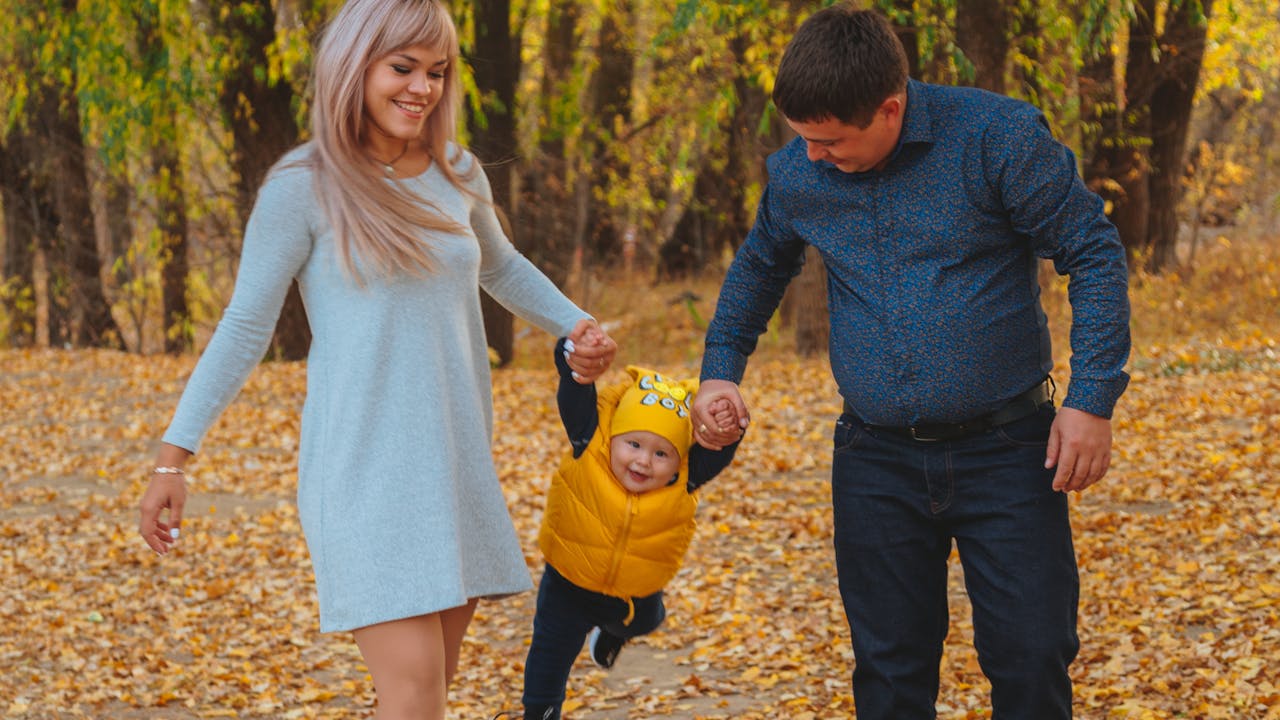 Happy family walking together in an autumn park with golden fall foliage