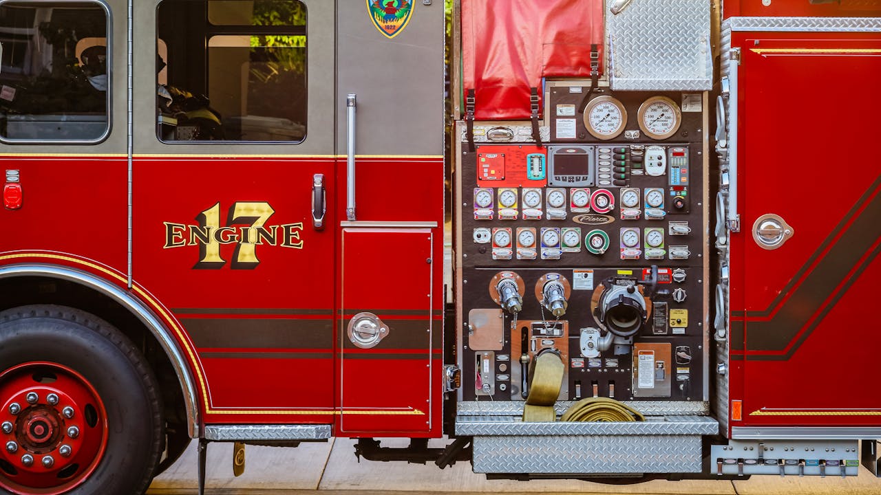 Red fire truck with equipment compartments and professional firefighting gear visible