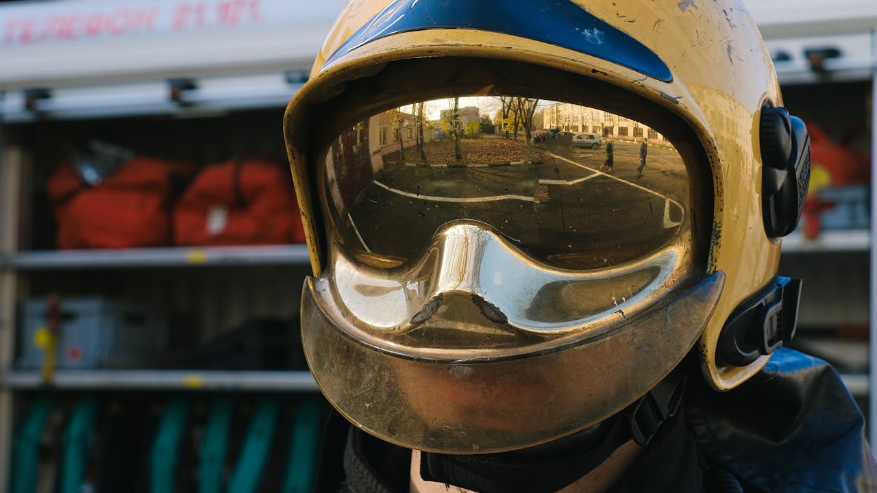 Firefighter in full bunker gear and helmet standing beside fire truck ready for action
