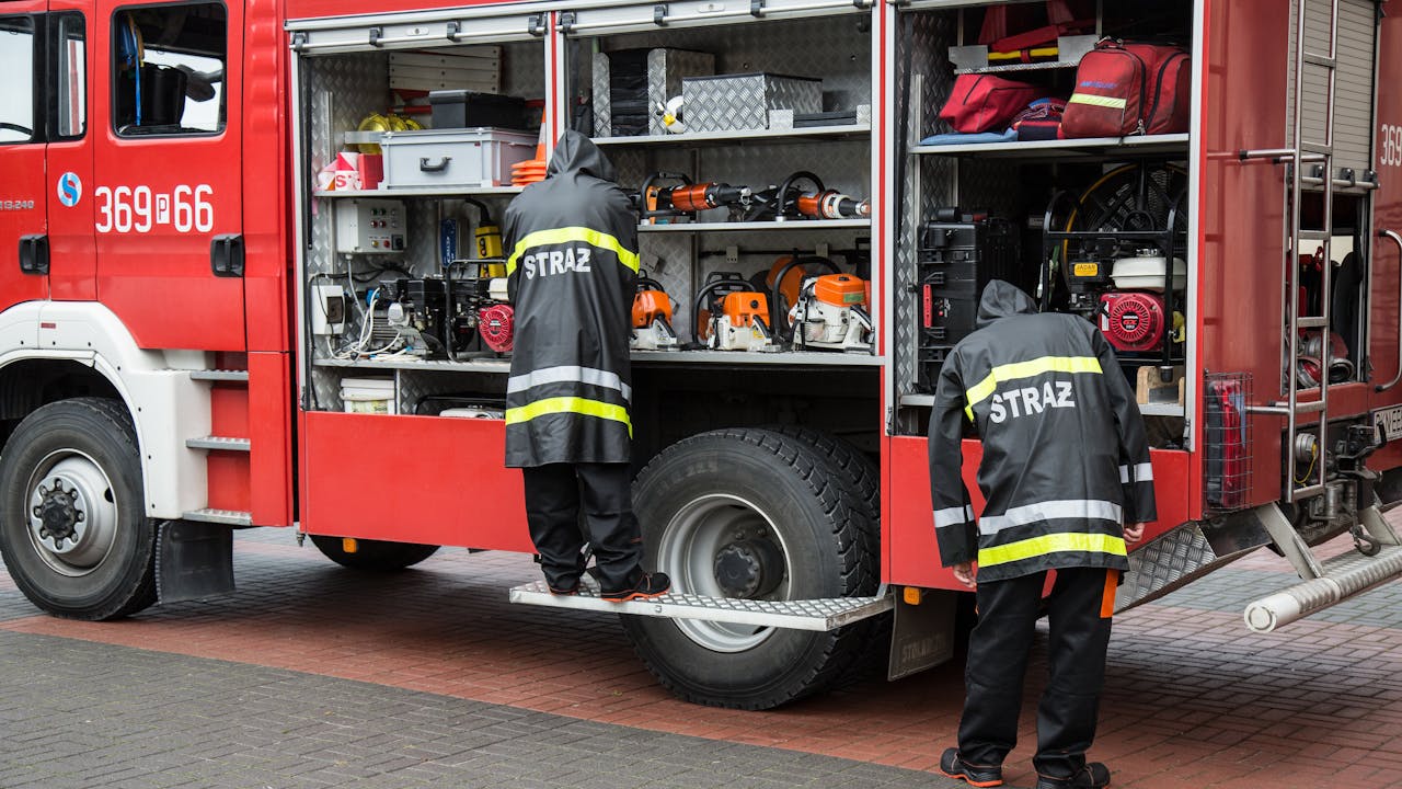 Firefighters standing together by red fire truck in urban setting demonstrating teamwork and readiness