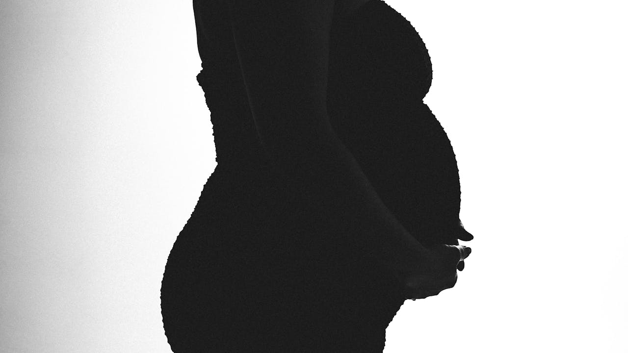 Silhouette of a pregnant woman in profile against bright light