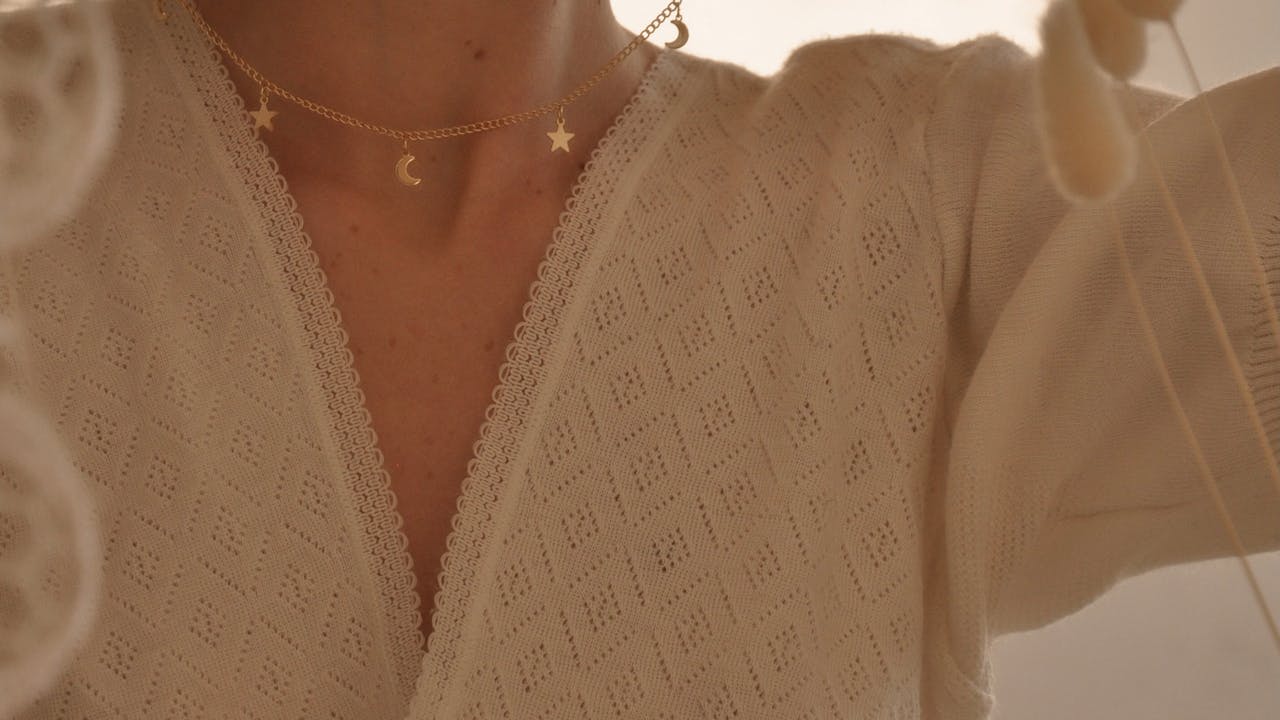 Woman carefully putting on a delicate pendant necklace