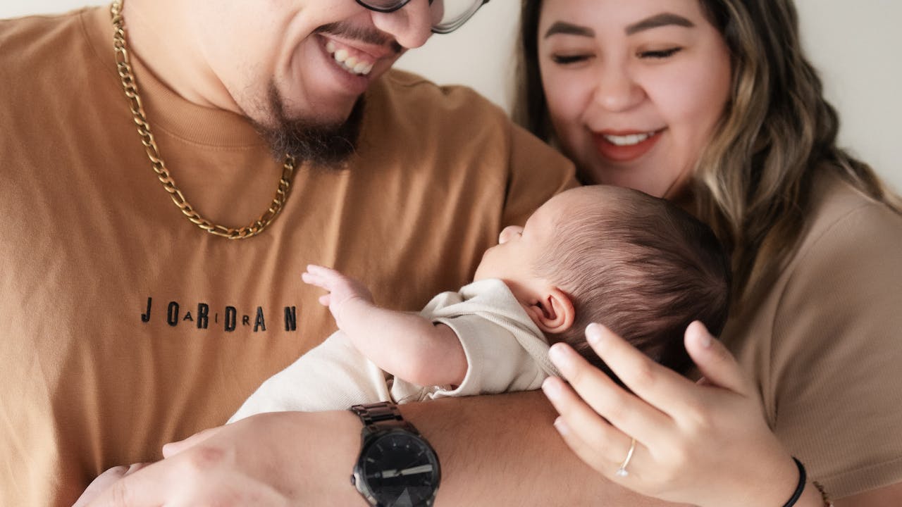 Couple sitting together on couch looking at new baby