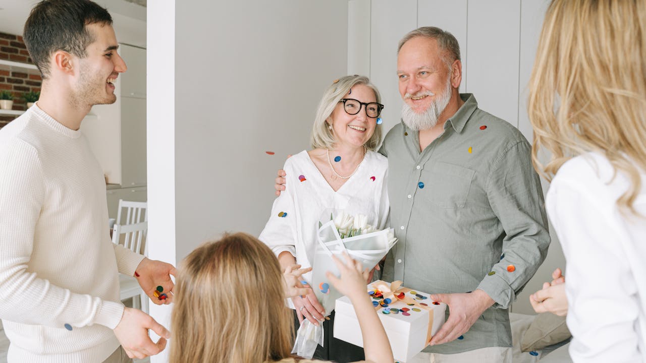 Senior couple holding flowers and a gift, celebrating a milestone occasion