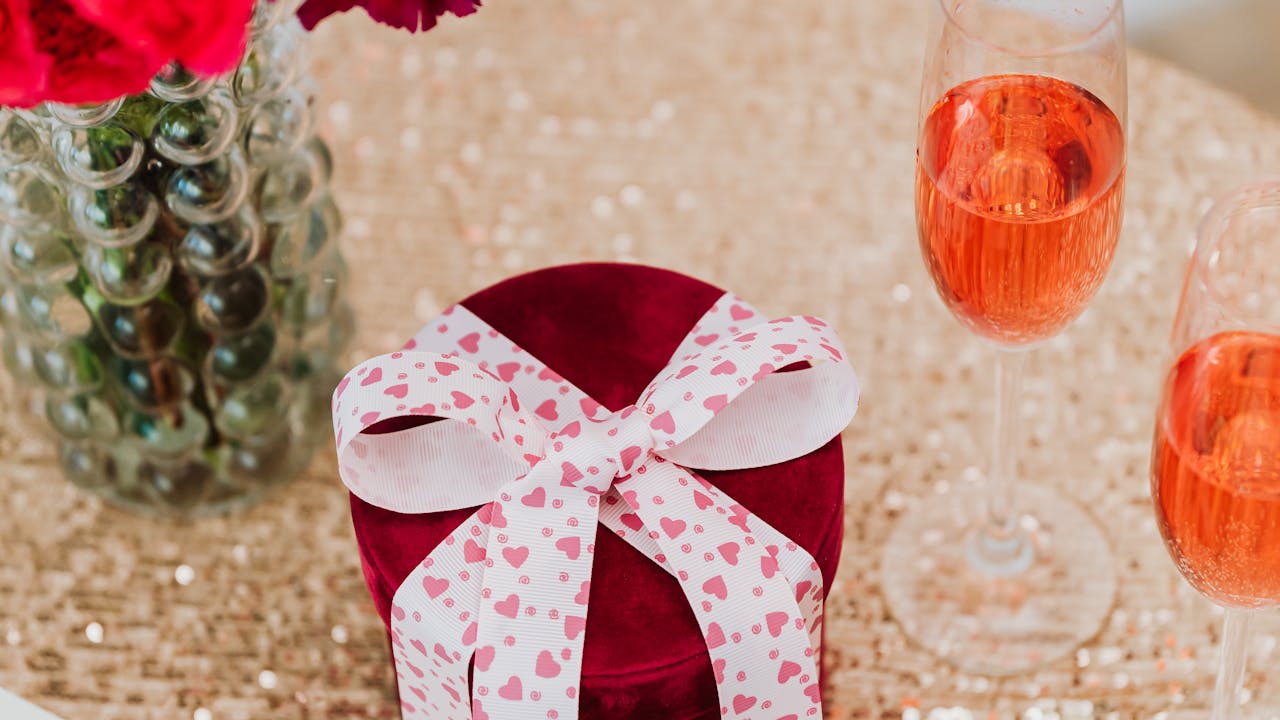 Valentine gift box with ribbon, champagne glasses, and red roses