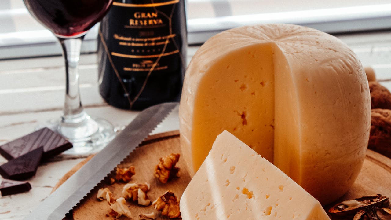 Wine bottle with glass, artisan cheese, and walnuts for a gourmet gift basket